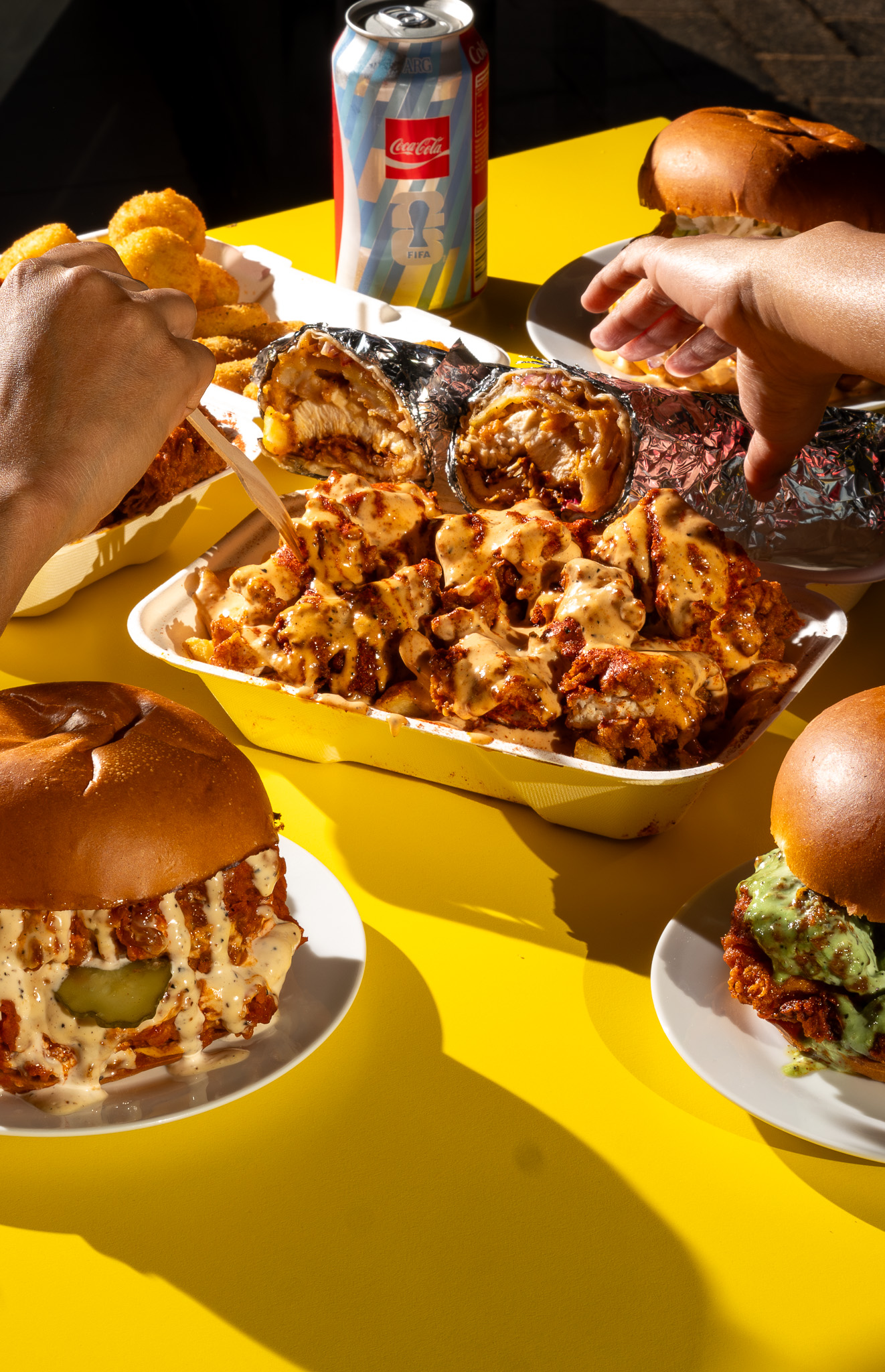 Spicy Chick spread on the yellow table with a loaded chicken box and sandos
